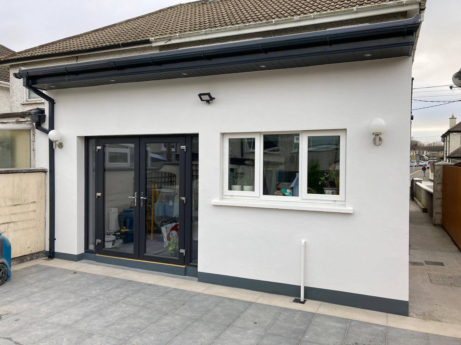 Finished white rendered rear extension with anthracite French doors and paved patio