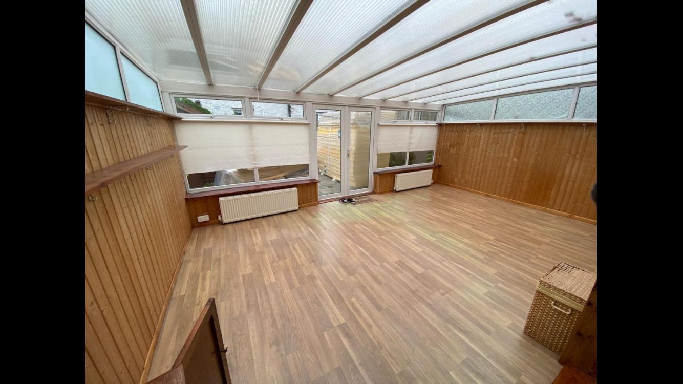 Bright timber-lined sunroom with glazed roof and wood-effect flooring