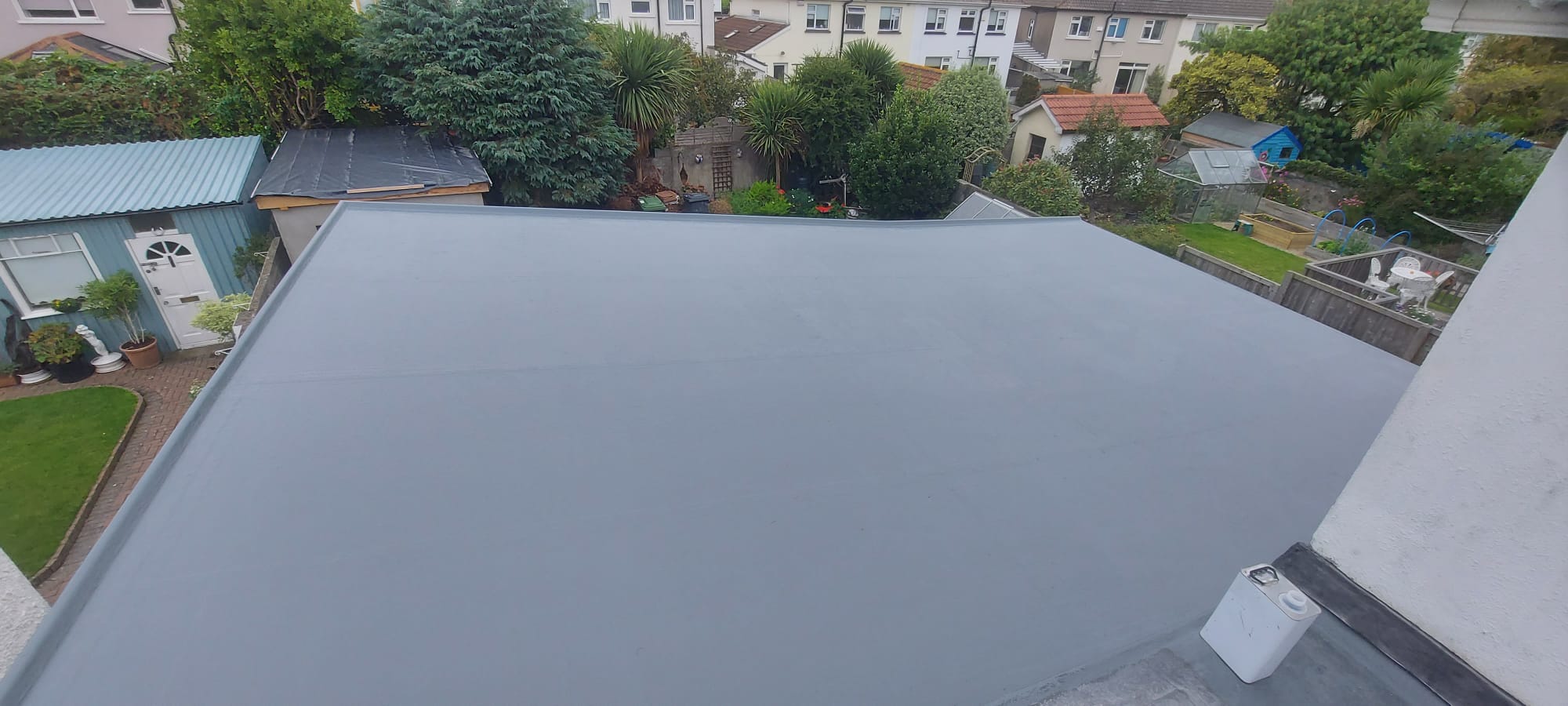 Aerial view of the completed flat roof surrounded by suburban gardens