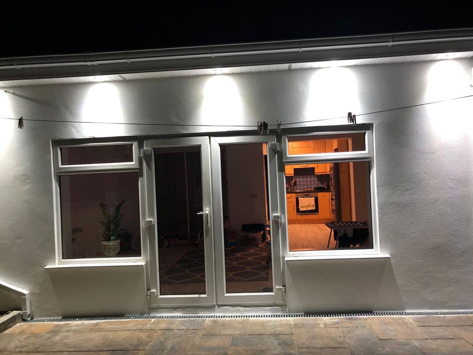 Extension exterior at night with illuminated windows and doors