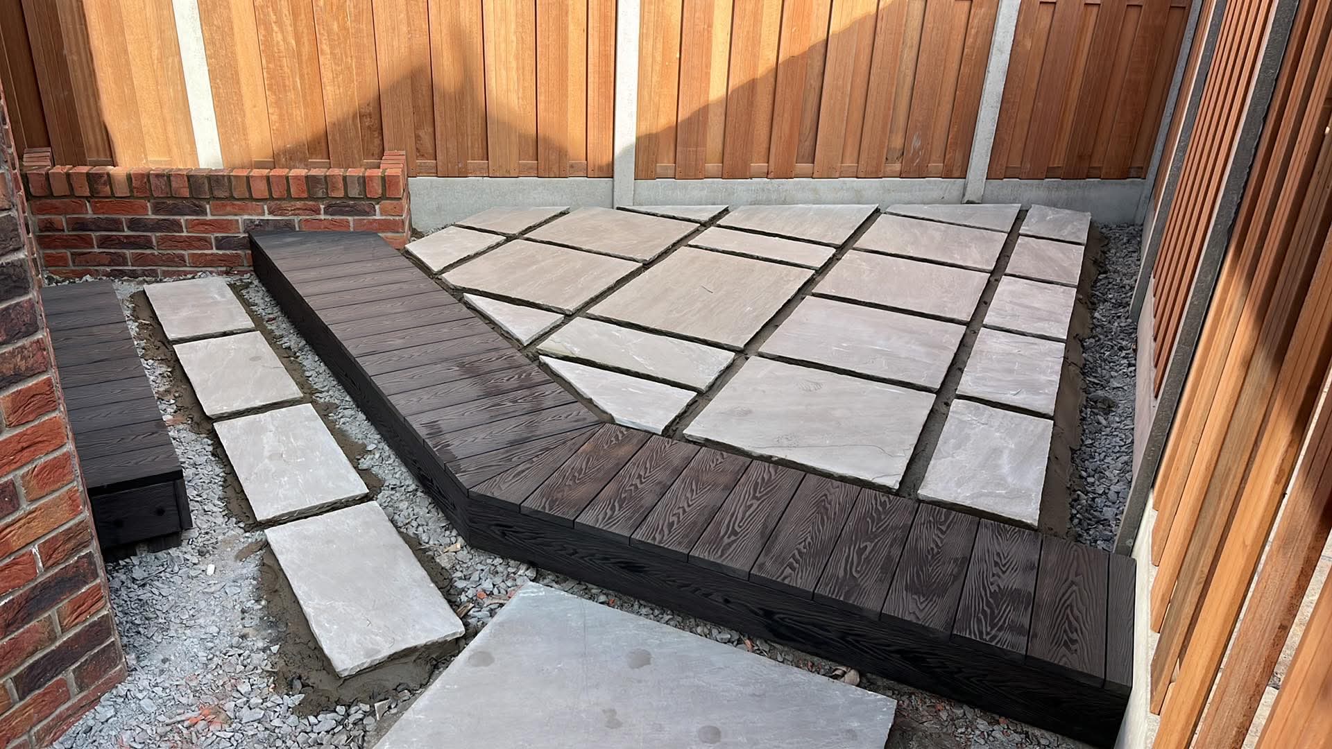 Rear garden with stone paving, timber decking and a new fence