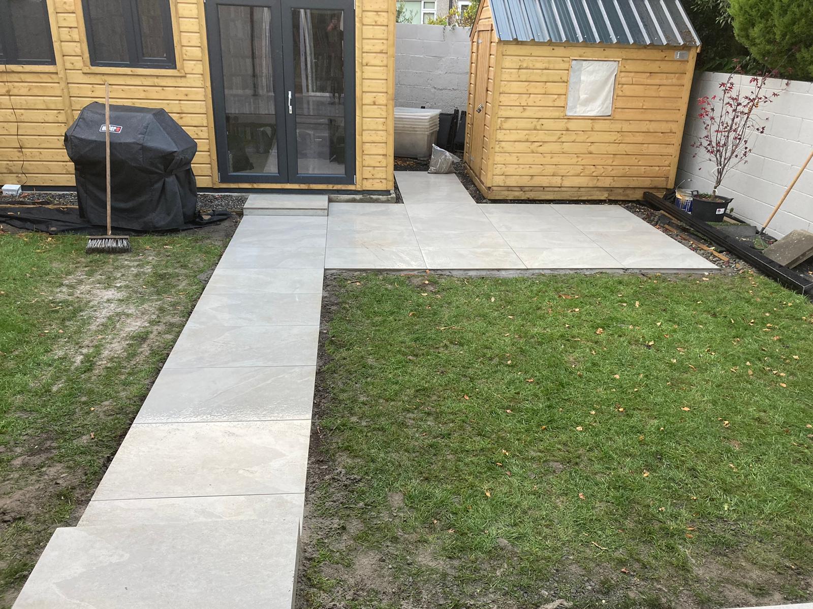 Porcelain pathway running across the lawn to a timber garden room
