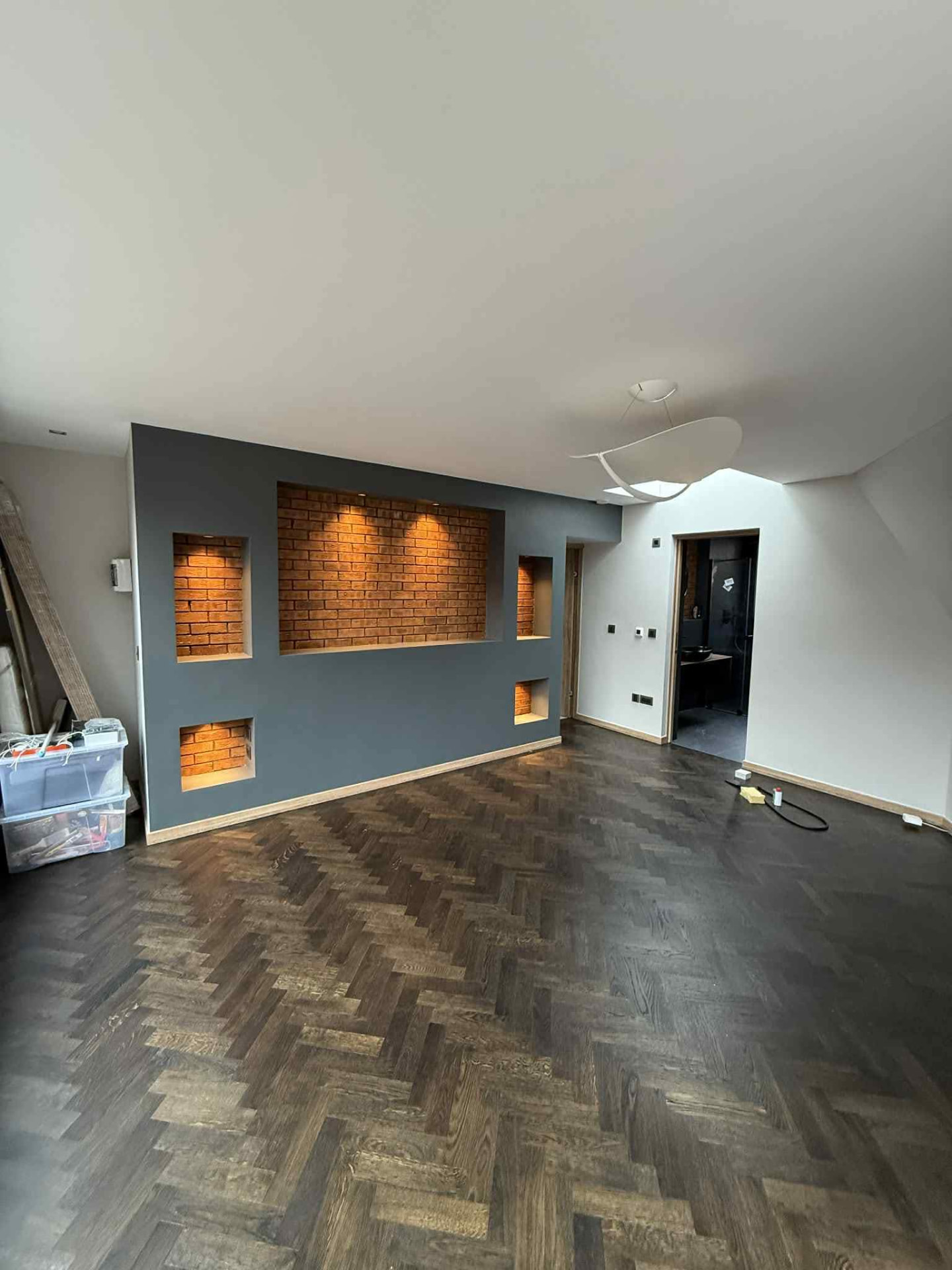 Living room with dark herringbone flooring and illuminated brick niches