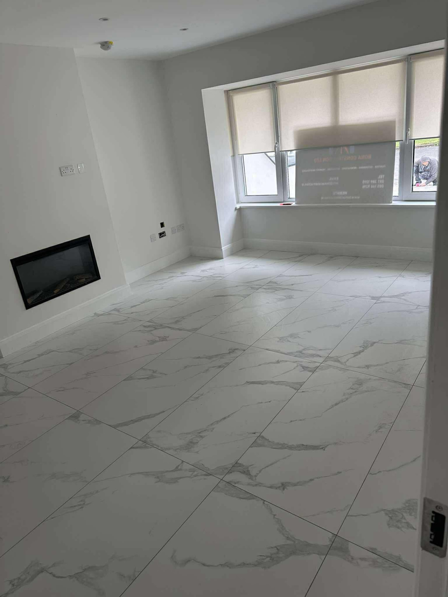 Finished living room with marble-style porcelain floor and media wall fireplace