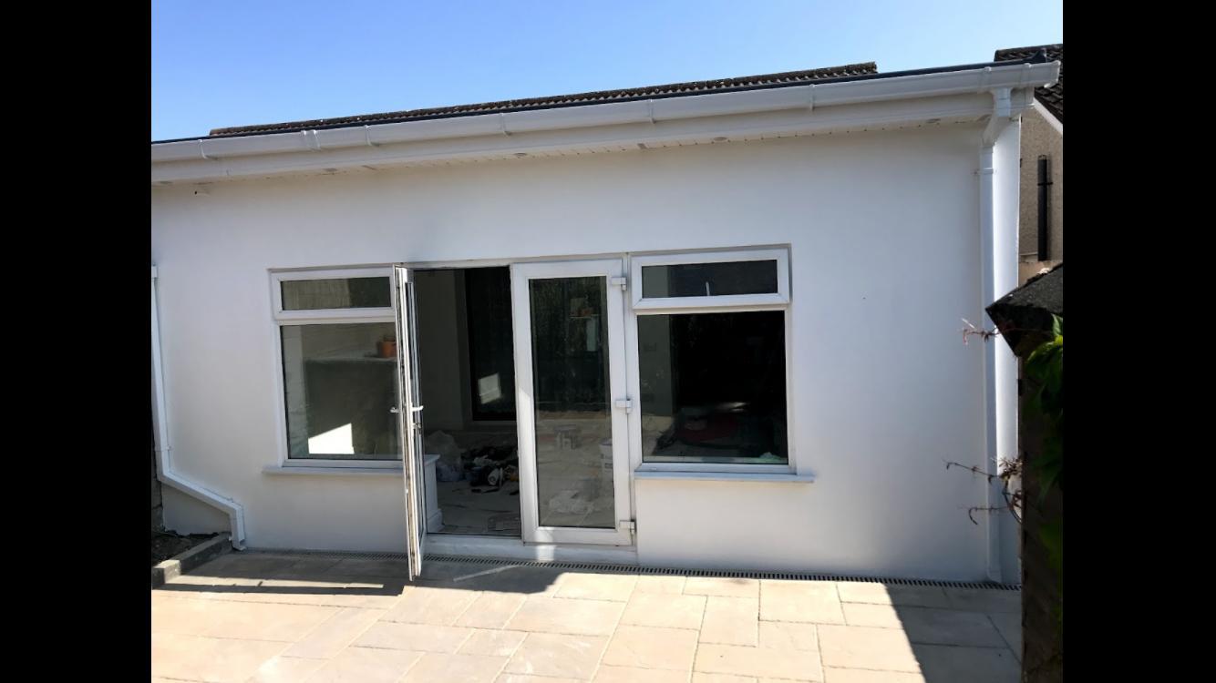 Finished white rendered extension with glazed doors and paved patio